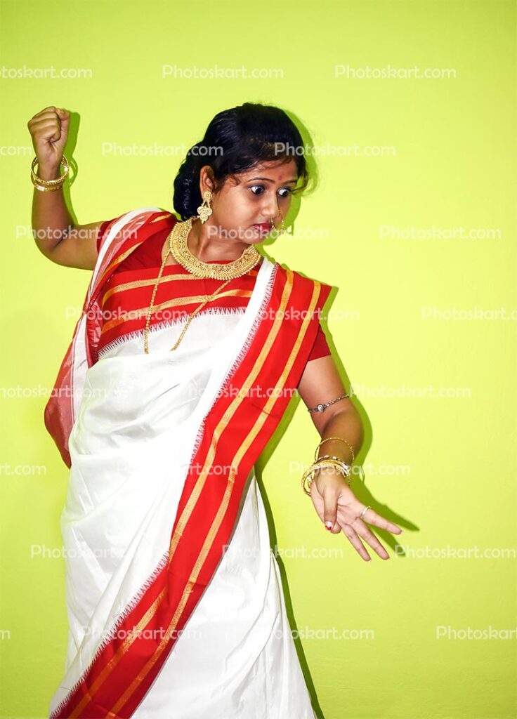 South Indian Woman in white saree standing against wall and looking at  flower decoration on the occasion of Onam Stock Photo - Alamy