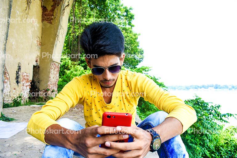 Young Boy Use Mobile Beside A River
