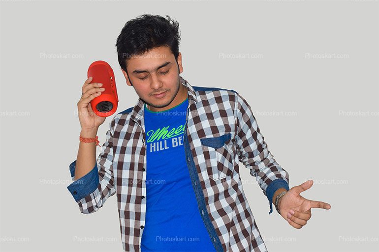A Smiling Indian Boy Listening Music With A Bluetooth Speaker
