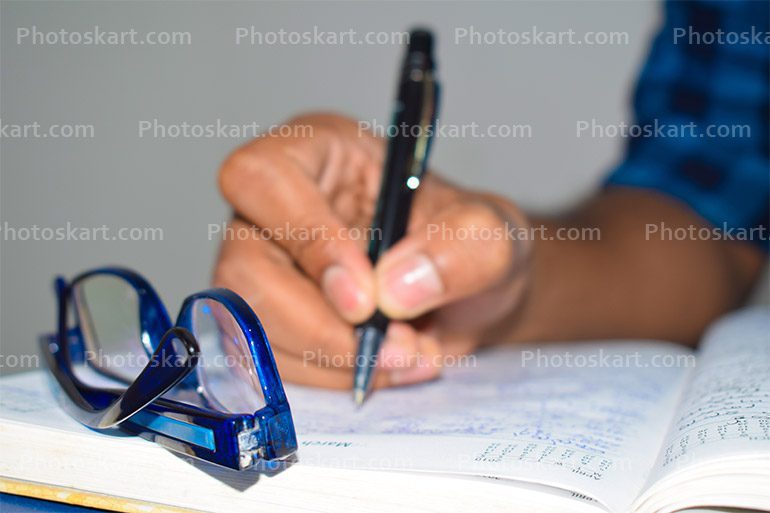 A Man Hand Writing Something On Notebook