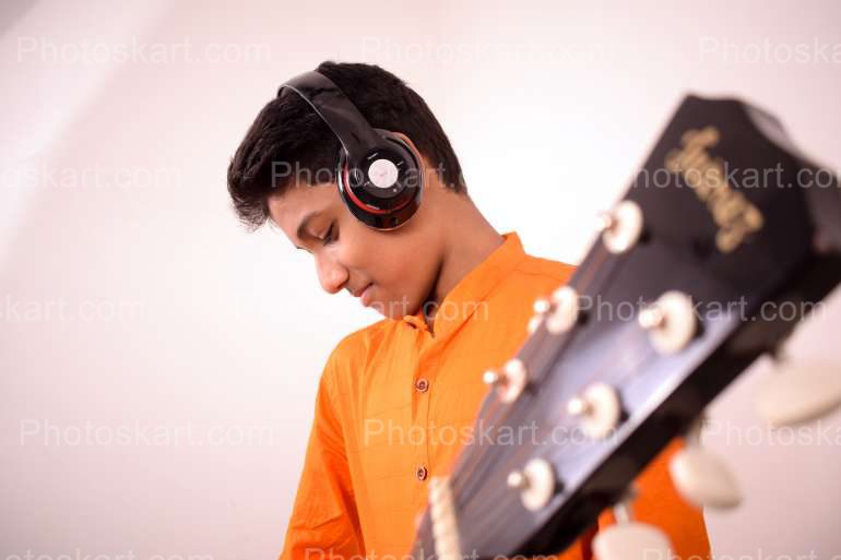 An Indian Boy With Orange Kurta Playing Guiter
