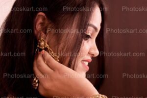 a smiling beautiful indian girl hands on earing image