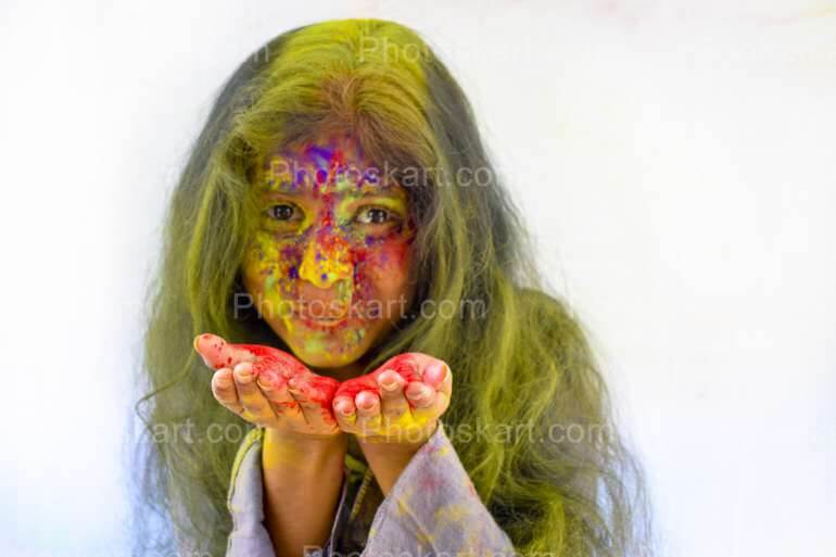A Young Indian Girl Blowing Off Colours From Her Hands During Holi Celebration