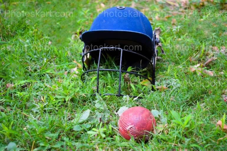 Cricket Helmet And Ball In A Field Royalty Free Stock Image