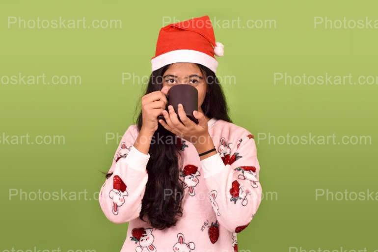 A Girl Drinking Coffee While Wearing Santa Cap