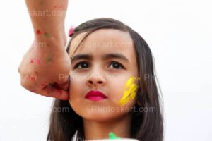 indian girl getting color on her face in holi festival