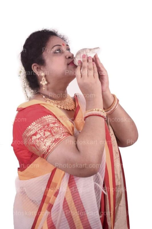 DG16823970922, bengali woman blowing on a conch shell stock photo, stock photos, hindu stock photos, traditional stock photos, bengali woman stock photos, agomoni photoshoot, puja photoshoot, girl, indian girl, indian cute girl, ma, culture, south asian culture, bengal, clay, clay idol, celebration, puja, festival, indian girl images, bengali festival, celebration, asia, bengali, festival costume, devi, beauty, face, clothing, ceremony, bridal, jewellery, durga model, festival season, durga puja look. girl with sari, sari, tradition, bengali tradition, god, durga puja look photo shoot with white and red saree, bengali saree, female, glamor, ethnicity, women, model, culture model, durga puja model, durga puja model hd image, puja model pose, festival model photoshoot, festival model images, lady, indian girl photoshoot, green background photoshoot, gorgeous, hindu girl, hindu girl photoshoot, stock, royaly, new